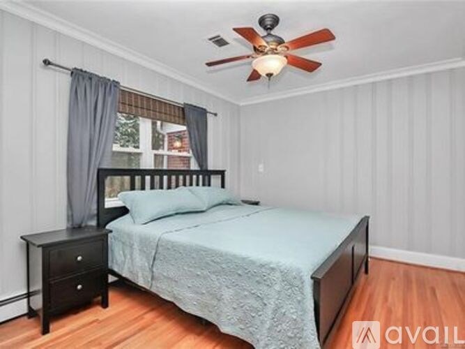 A bedroom with a bed, nightstand, and window.