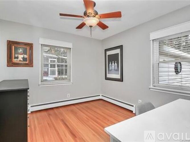 A room with a ceiling fan and two pictures on the wall.