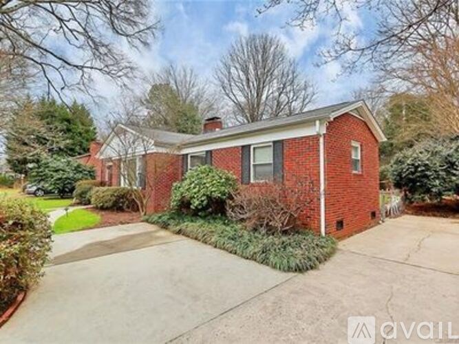 A red brick house with a white roof and a driveway in front.
