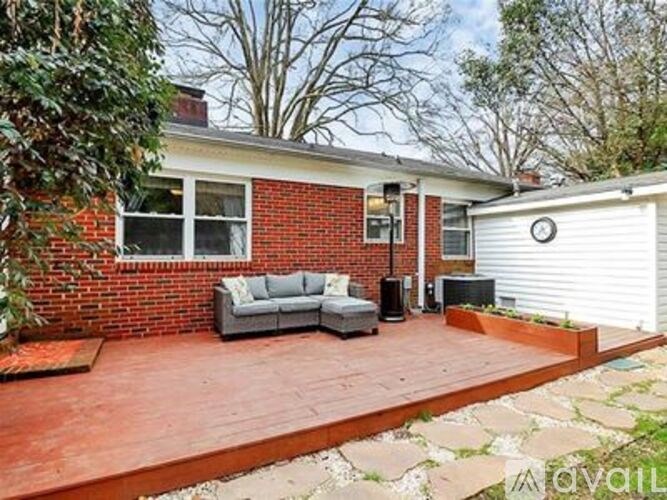 A red brick house with a white garage door and a grey couch on a red brick patio.