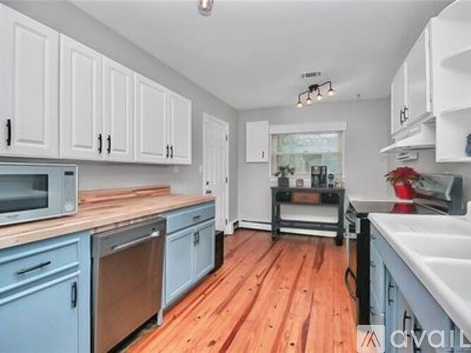 A kitchen with wooden floors and white cabinets.