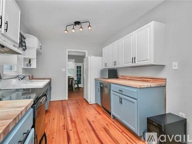 A kitchen with wooden floors and a mix of white and blue cabinetry.