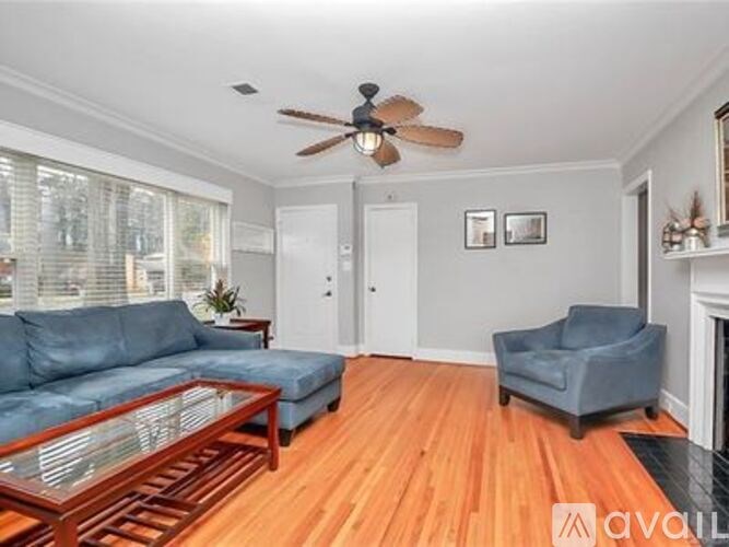 A living room with a blue couch, a glass coffee table, and a ceiling fan.