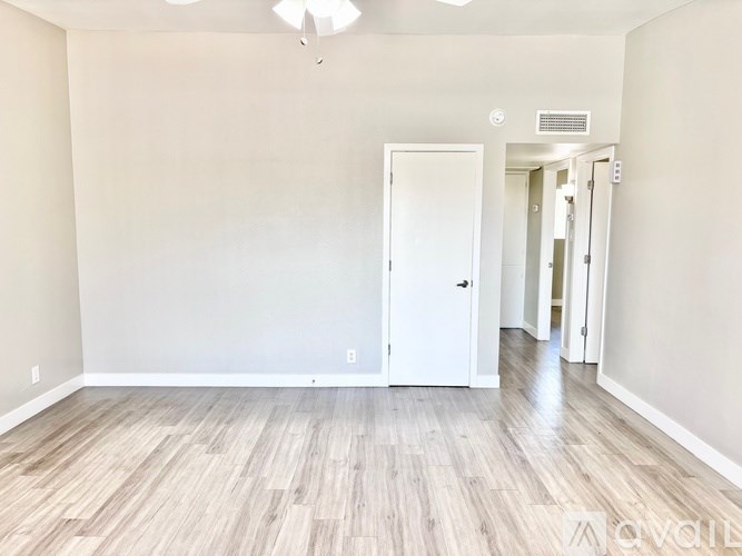 A room with a white door and wooden flooring.