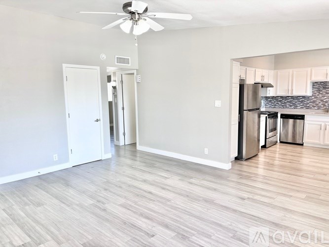 A spacious kitchen with a refrigerator, oven, and a ceiling fan.