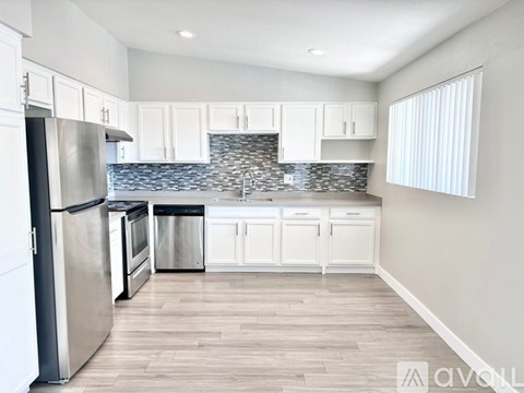 A kitchen with white cabinets and a stainless steel refrigerator.