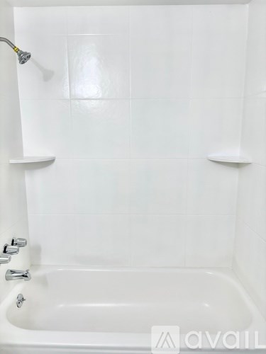 A white bathtub with a shower head and faucet.