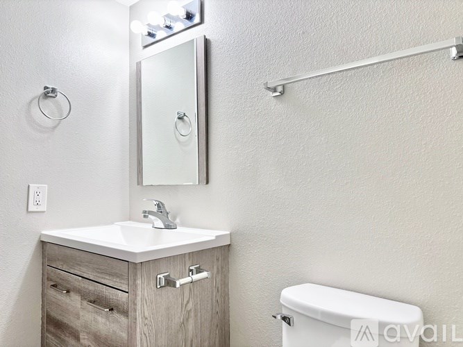 A bathroom with a white sink, a mirror, and a toilet.