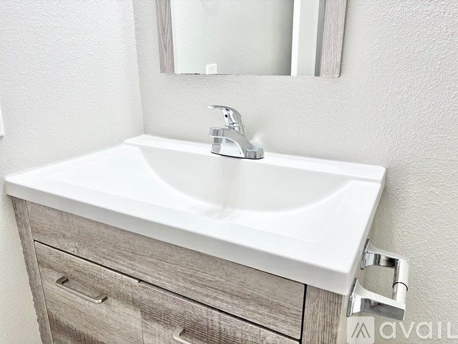 A white sink with a silver faucet and a mirror above it.