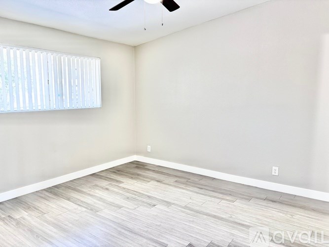 A room with a ceiling fan and a window with blinds.