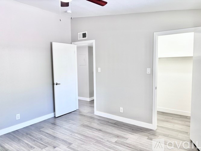 A room with a white door and a fan on the ceiling.