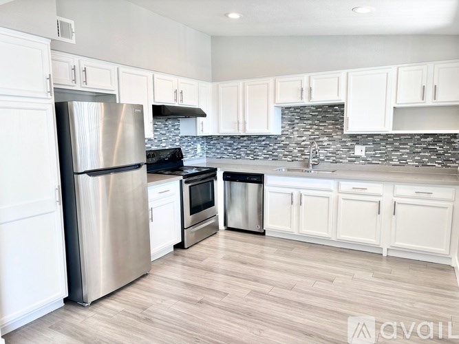 A kitchen with white cabinets and a stainless steel refrigerator.