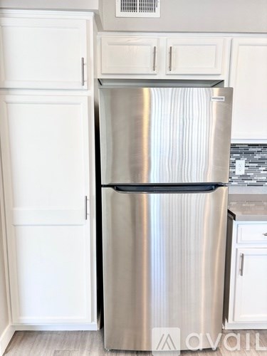A stainless steel refrigerator with a black bottom drawer.