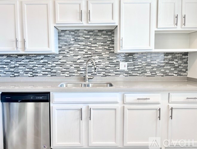 A kitchen with white cabinets and a stainless steel dishwasher.