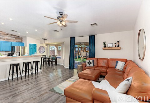 A living room with a brown leather couch and a ceiling fan.