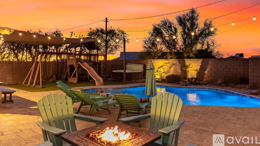 A backyard with a pool, a fire pit, and a slide.