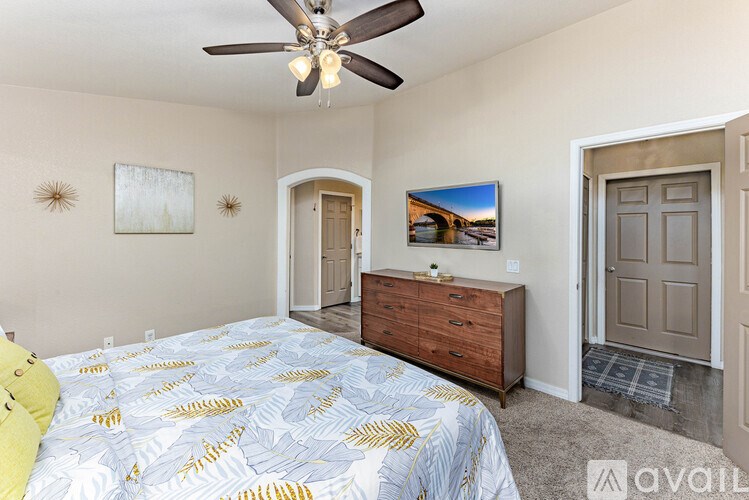 A bedroom with a bed, dresser, and a ceiling fan.