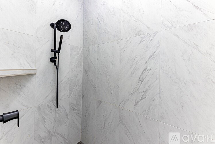 A shower head mounted on a wall with a marble pattern.