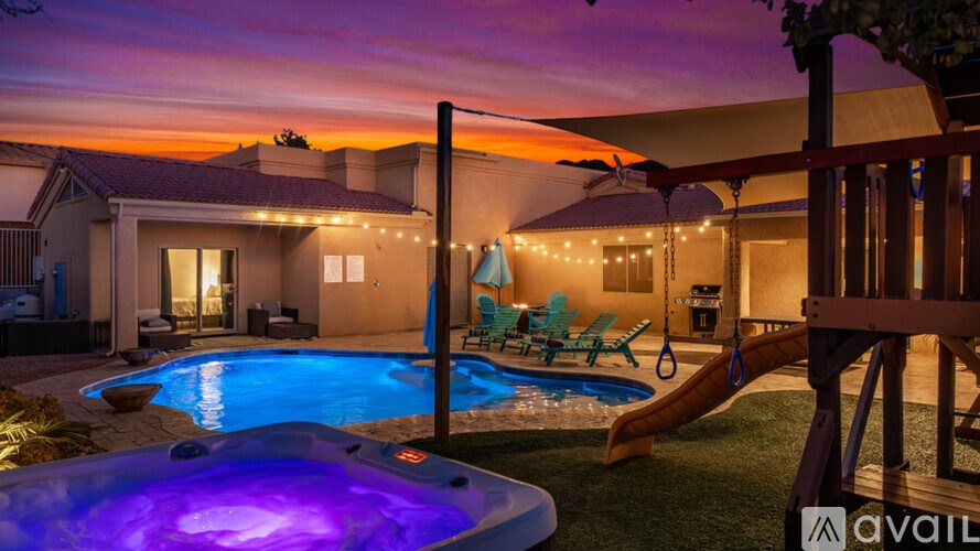 A hot tub sits in the middle of a backyard with a deck and patio area.