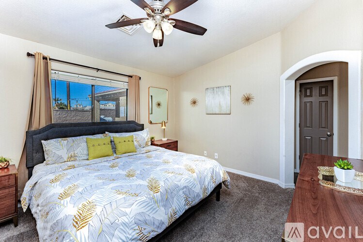 A bedroom with a bed, a ceiling fan, and a window with a view of the outdoors.