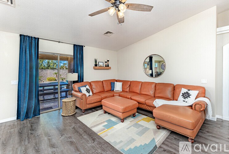 A living room with a large orange sectional sofa and a round mirror on the wall.