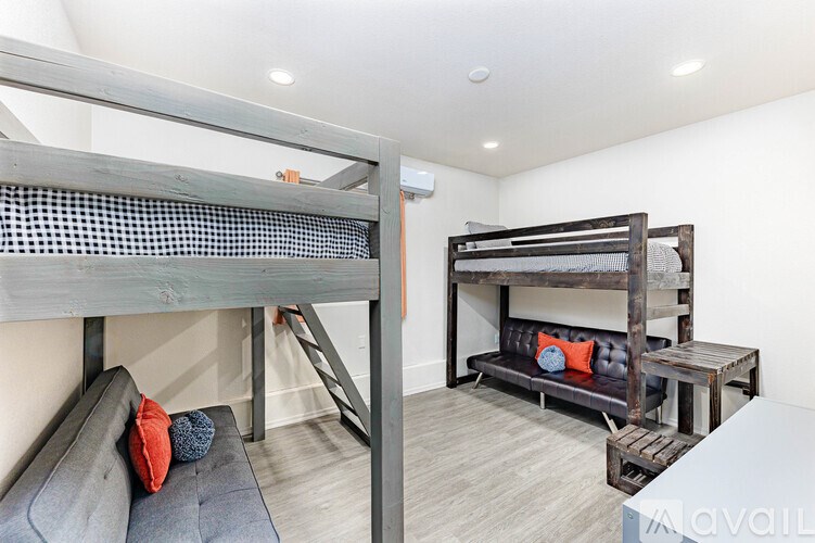 A room with a bunk bed and a loft bed with a couch and pillows on the floor.