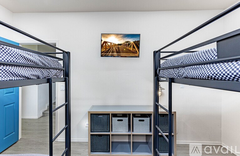 A room with two bunk beds and a desk with storage.