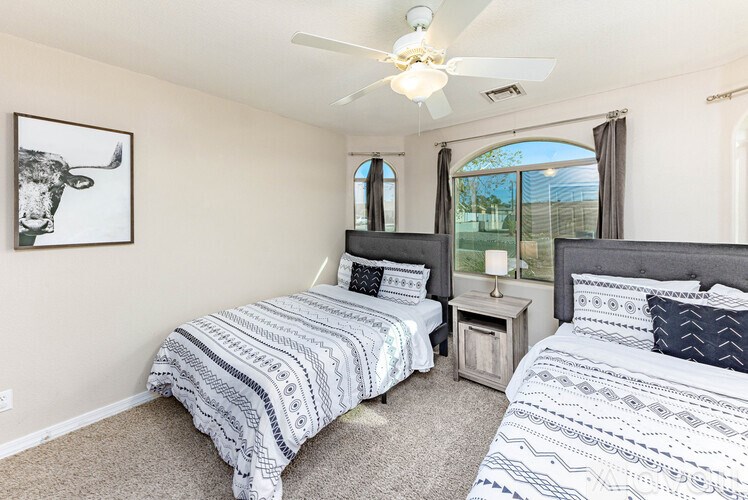 A bedroom with two beds and a ceiling fan.