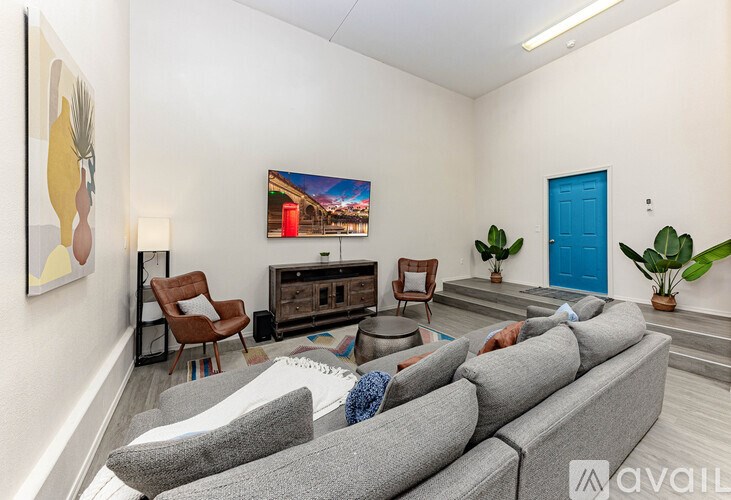 A living room with a grey sofa, a wooden coffee table, a television, and a painting on the wall.