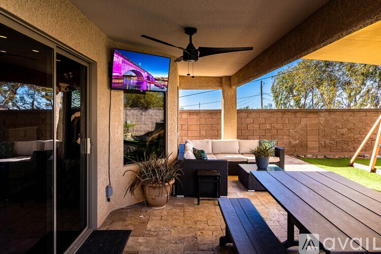 A patio with a table, chairs, and a ceiling fan.