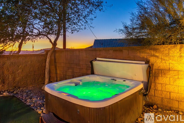 A hot tub with a green light inside is surrounded by a wooden fence.