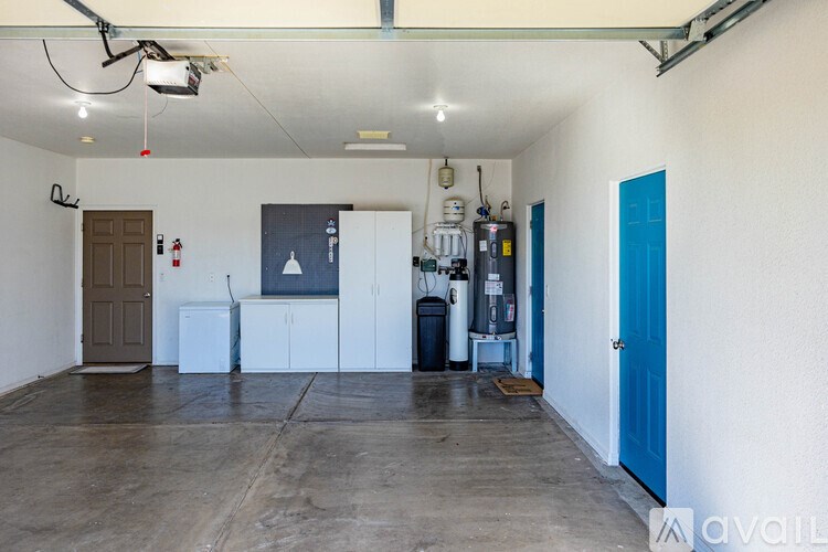 A large empty room with a white ceiling and a blue door.