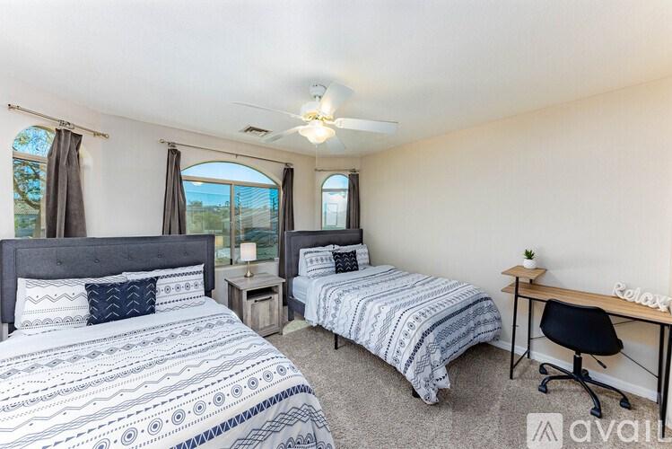 A bedroom with two beds and a desk.
