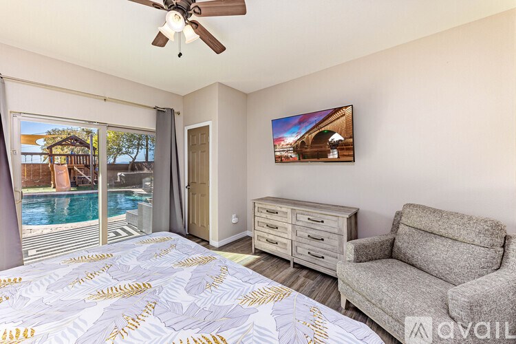 A bedroom with a bed, a couch, a ceiling fan, and a television.