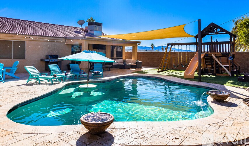 A pool with a slide and a sunshade.