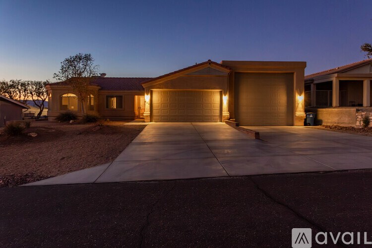 A house with a driveway and garage is lit up at dusk.
