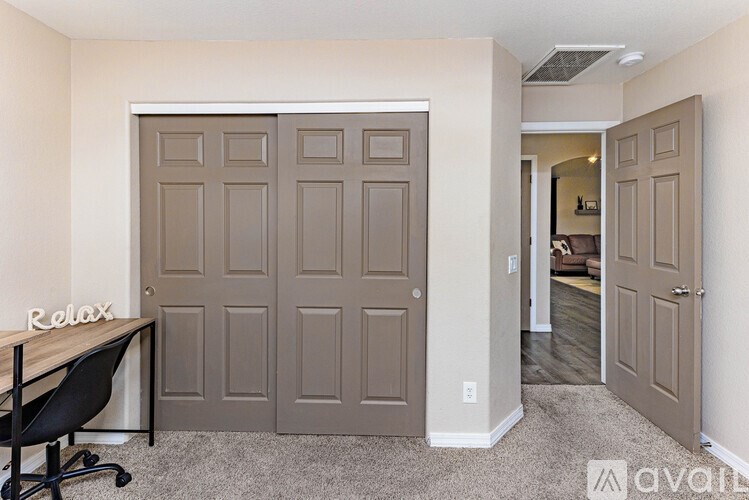 A room with a brown door and a black chair.