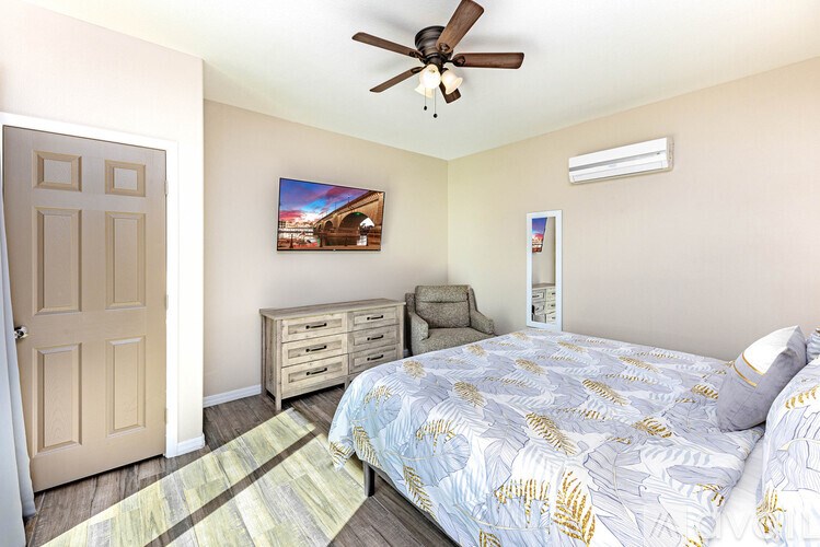 A bedroom with a bed, dresser, and a ceiling fan.