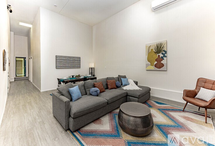 A living room with a grey couch, a brown chair, and a rug.