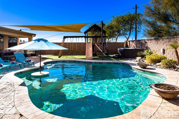 A pool with a blue umbrella and a yellow awning.