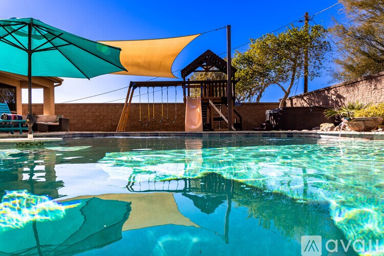 A pool with a blue sky and a yellow umbrella.