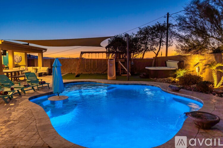 A pool with a blue umbrella and chairs around it.