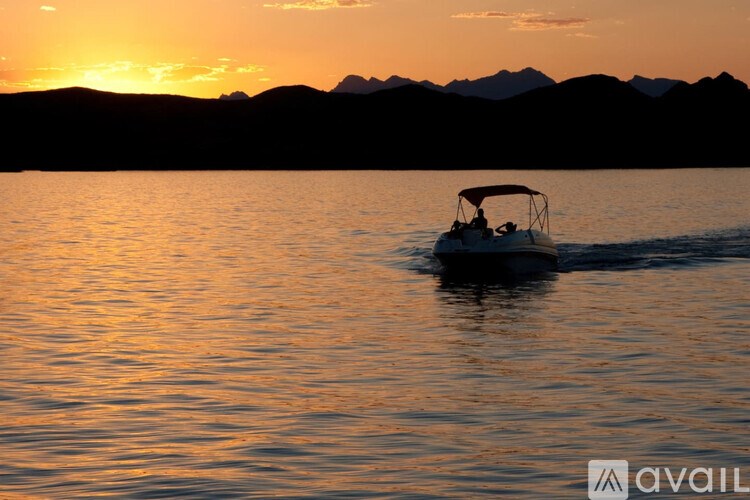 A boat is sailing on the water with a sunset in the background.