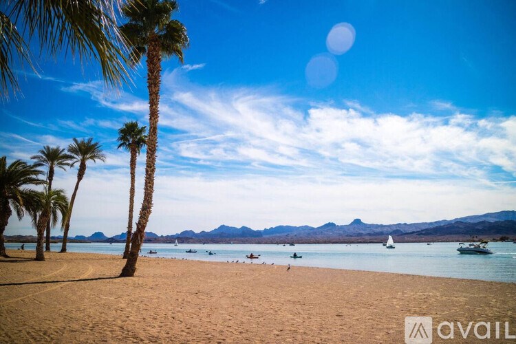A beach scene with palm trees and boats in the water.