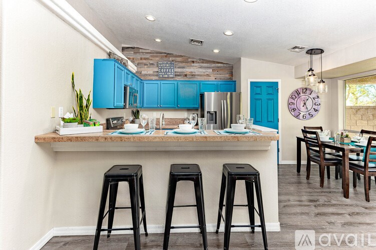 A kitchen with blue cabinets and a bar area with stools.