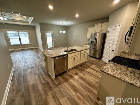 A kitchen with a granite countertop and a stainless steel refrigerator.