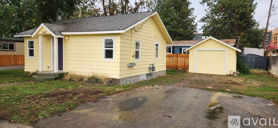A small yellow house with a black roof and a white door is available for purchase.