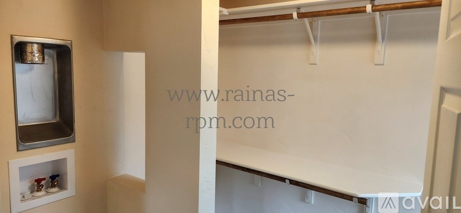 A white wall with a small shelf and a white door.