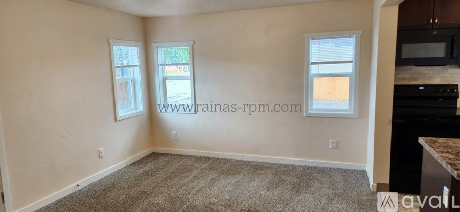 A room with a carpeted floor and two windows.