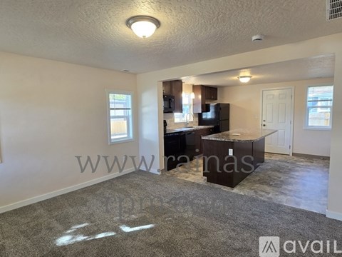A living room with a grey carpet and a brown cabinet.
